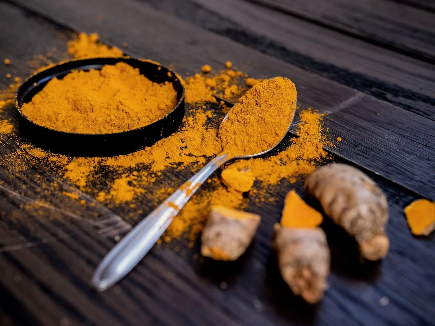 Turmeric powder in a bowl with fresh turmeric roots
